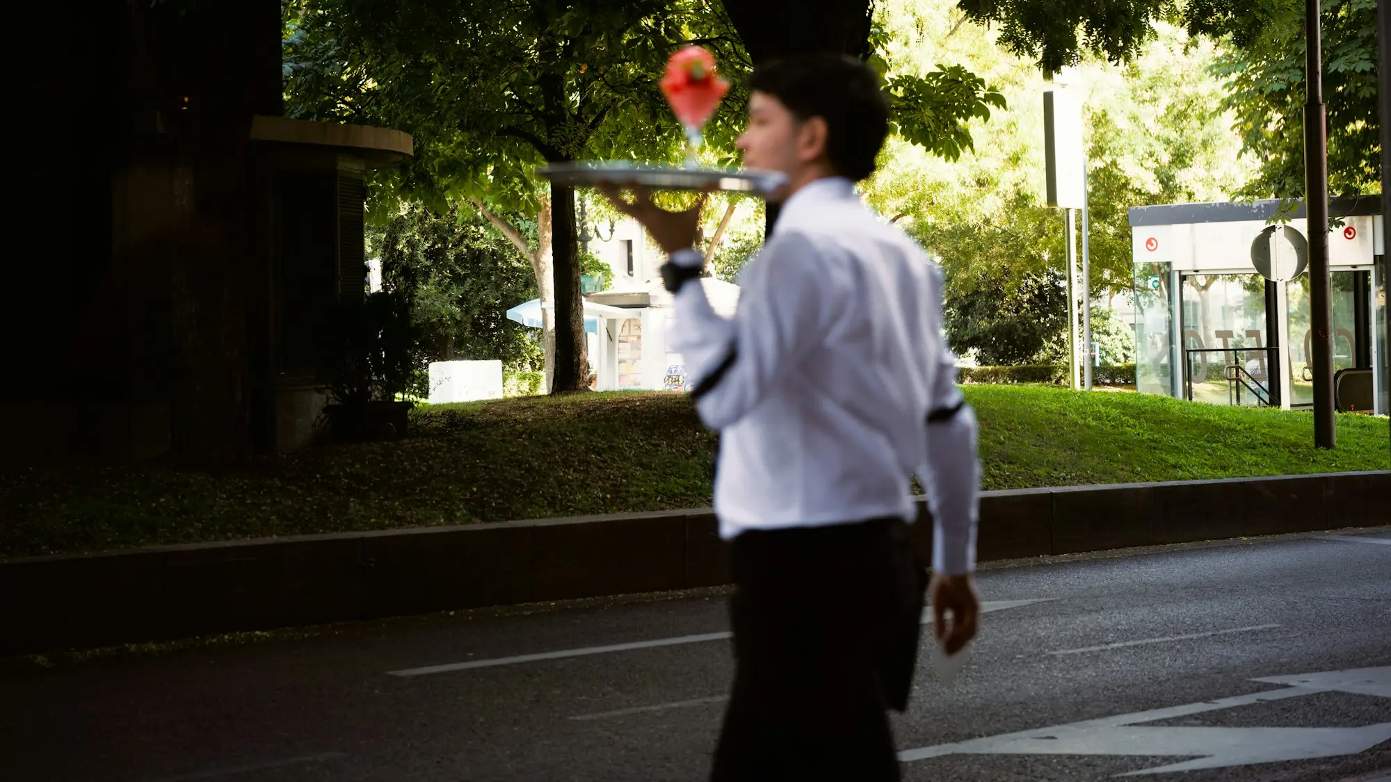 Waiter carrying a tray with a drink at an outdoor cafe