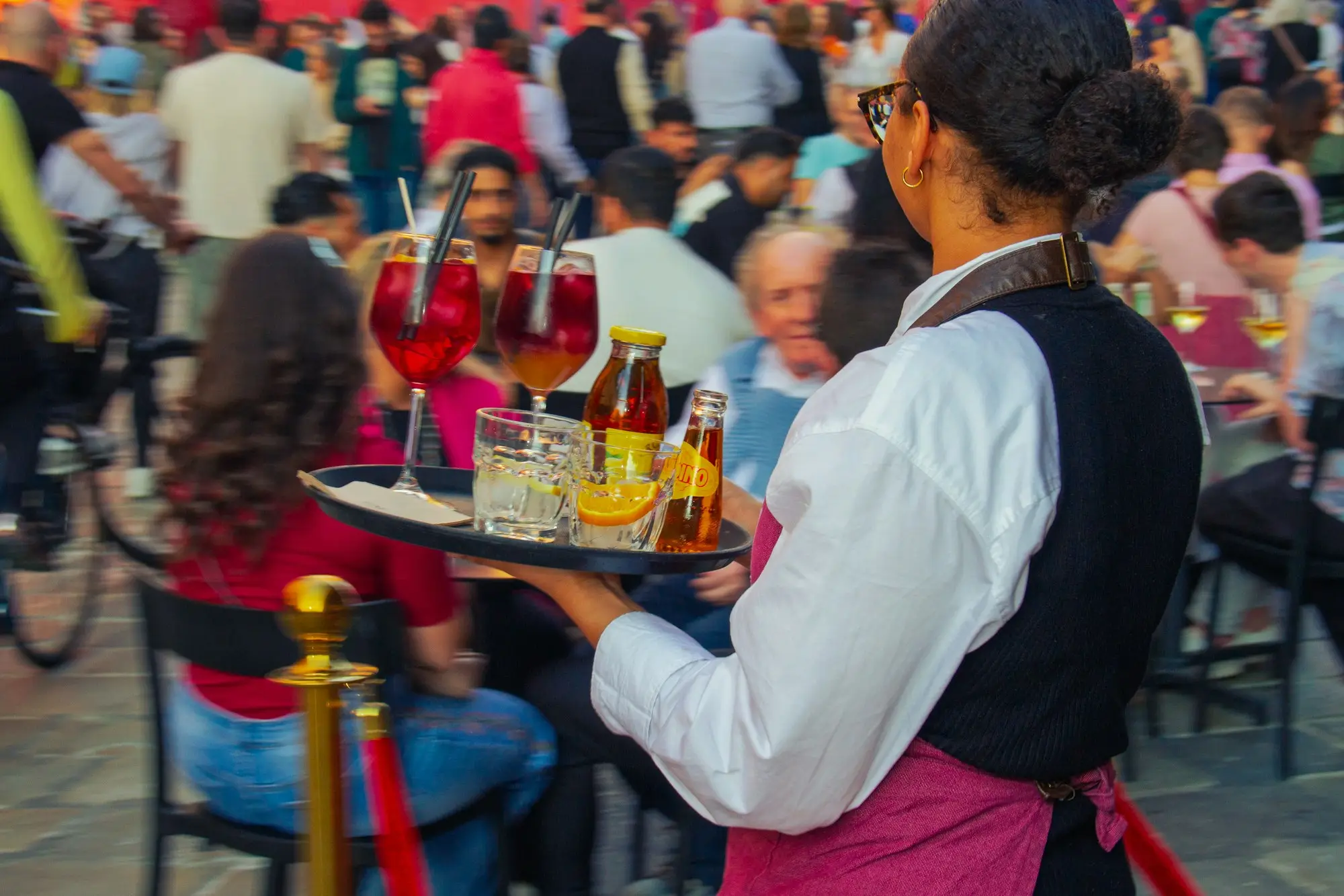 Server carrying drinks and bottles on a tray