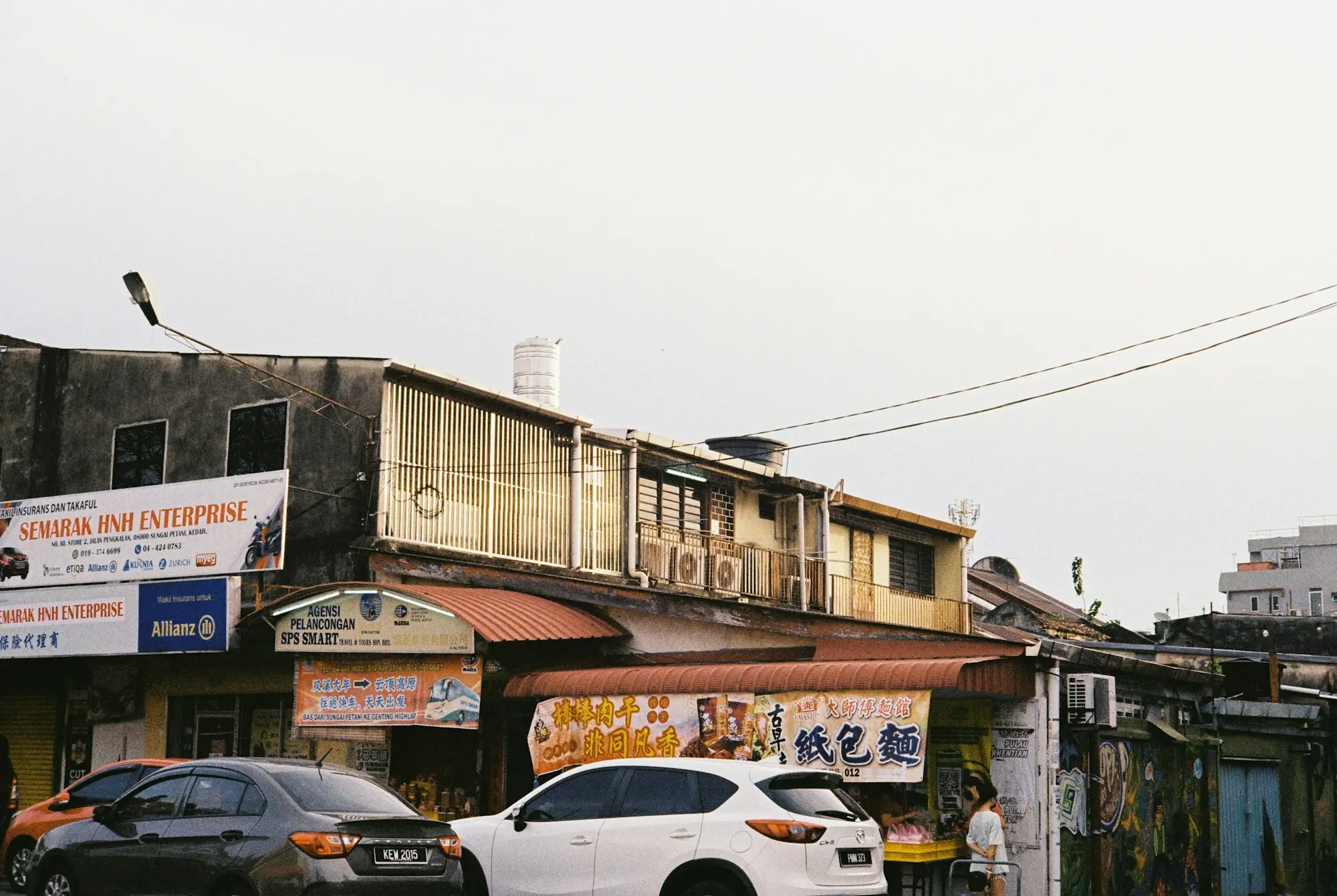 Cars passing old shopfront buildings with signs